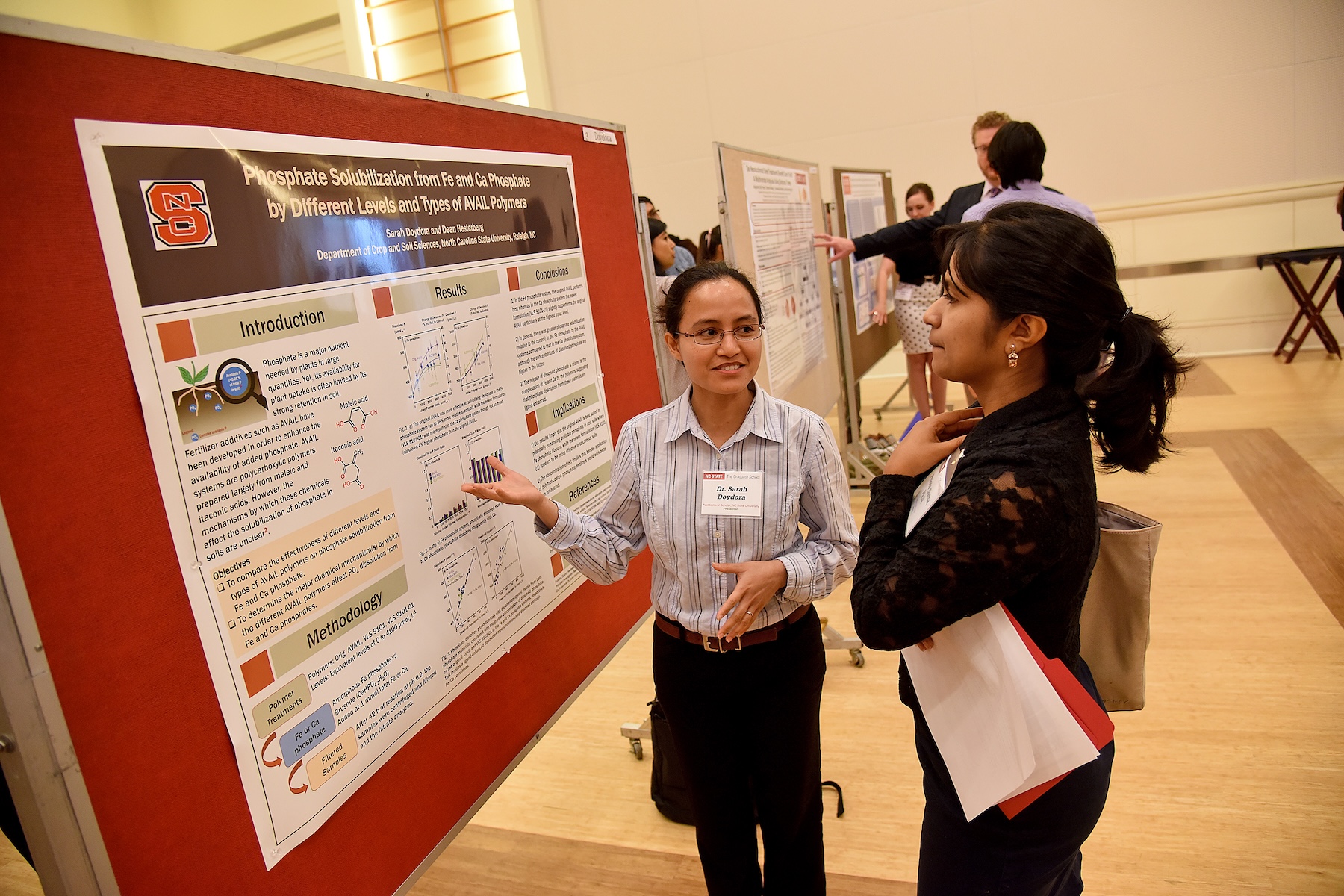 A student presenting her senior design poster to an event attendee