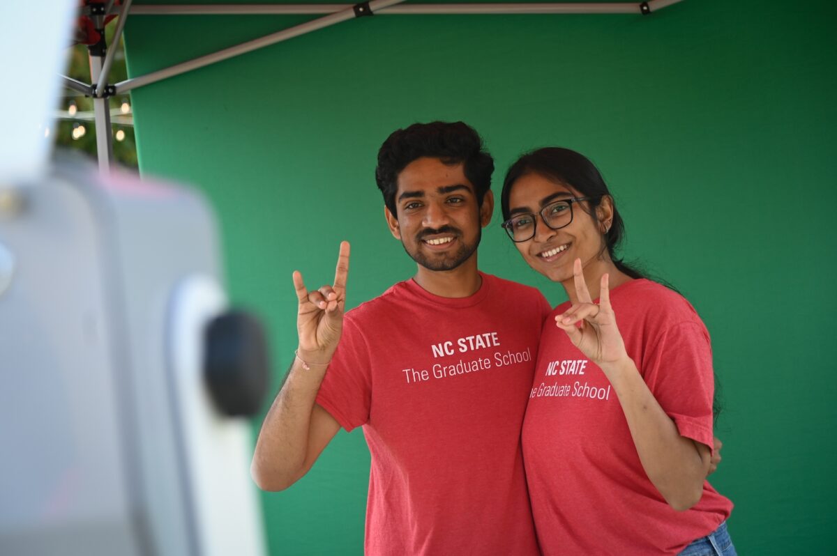 Two students representing The Graduate School flash their wolf hand sign