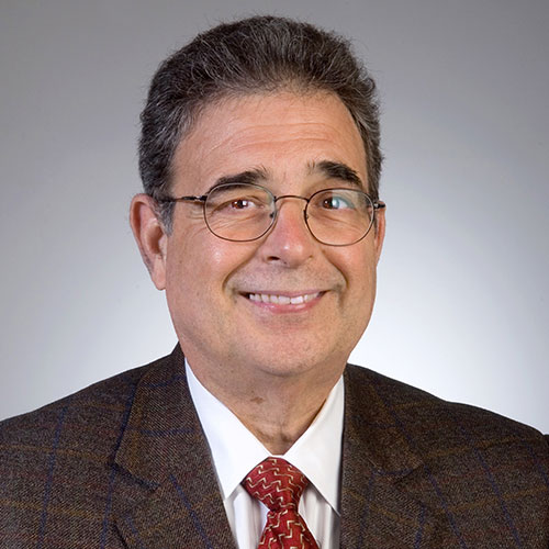 man with glasses and in a suit smiling
