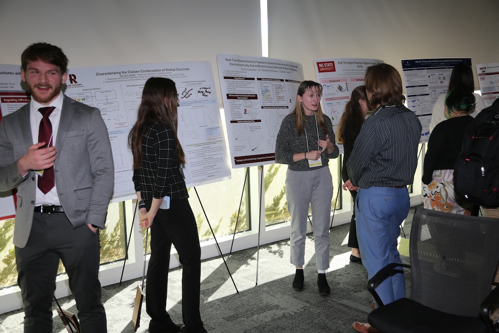 woman explains her research poster to guests