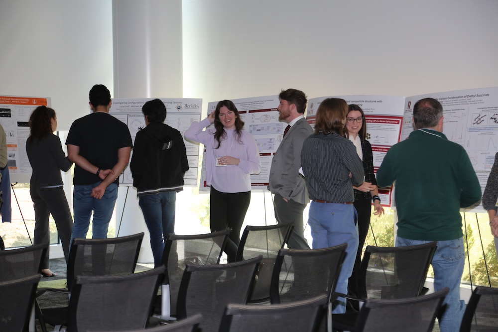 photo of many people discussing their research posters to guests