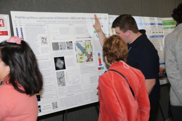 candid photo of a man explaining his research poster