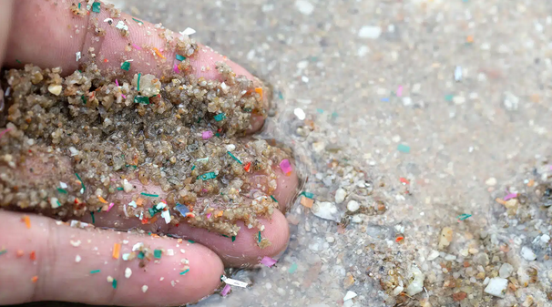 A close-up shot of microplastic waste mixed in with seaside sand.
