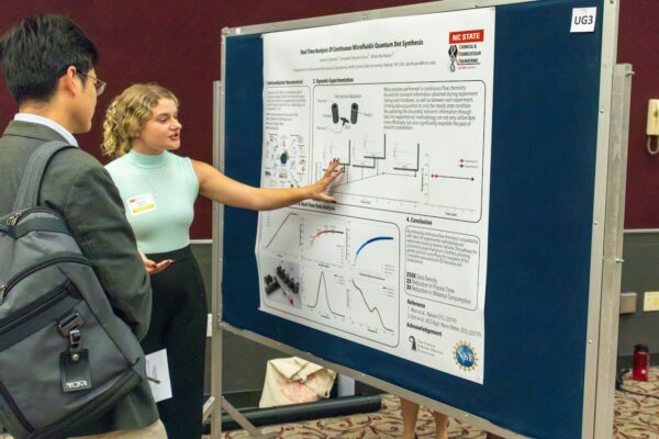 man and woman stand in front of a research poster discussing it
