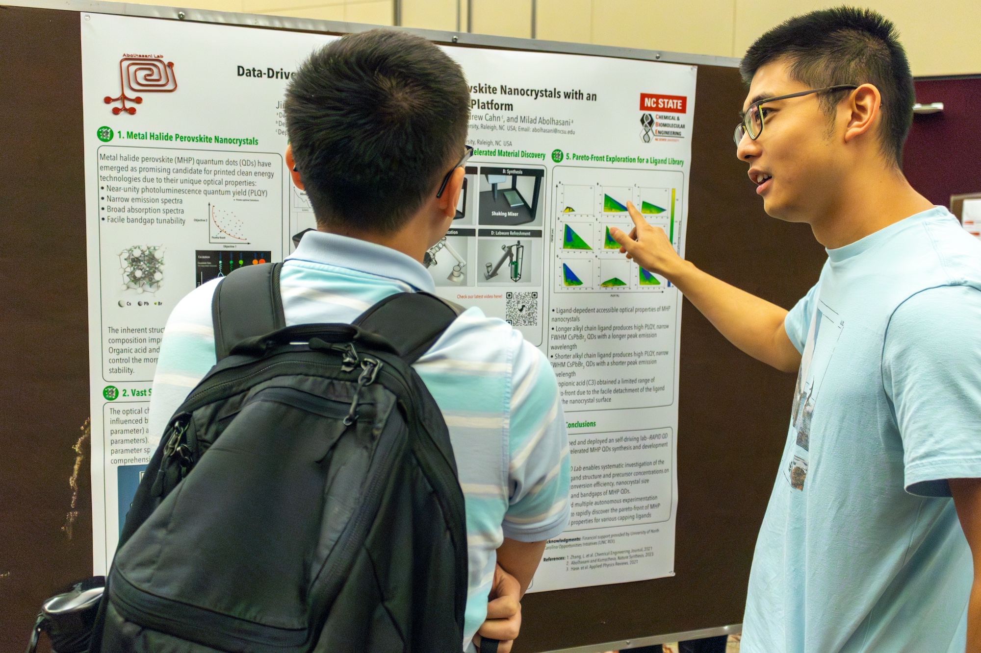 two men discuss a research poster