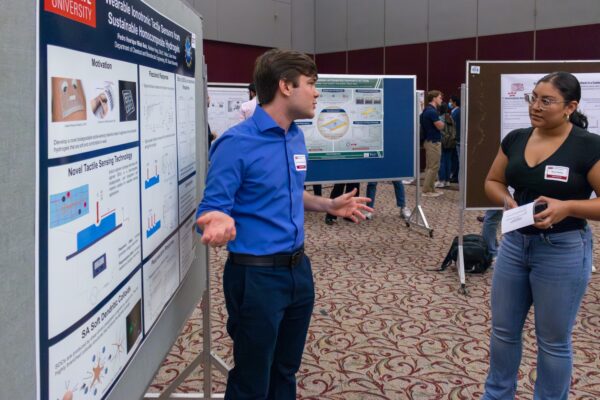 a man and a woman discuss his research poster
