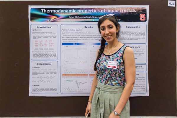 a woman poses in front of her research poster